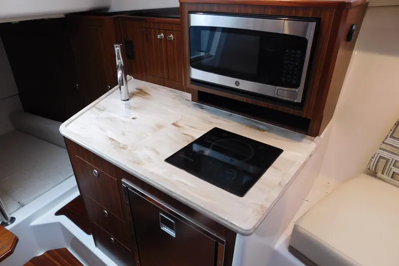 Slide: The Image of 2023 Pursuit OS 325 Offshore boat kitchen with microwave, sink, and stove. - 43