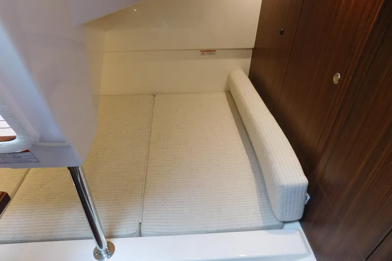 Slide: The Image of 2023 Pursuit OS 325 Offshore cabin interior with cushioned seating and wooden paneling. - 44