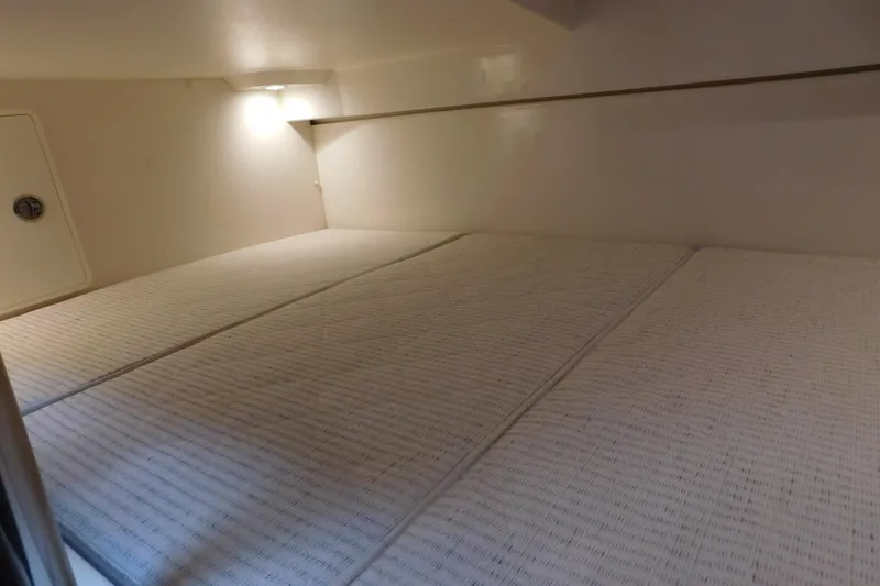 Slide: The Image of 2023 Pursuit OS 325 Offshore cabin interior with cozy bedding and soft lighting. - 45