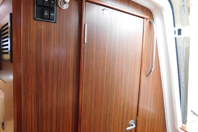 Slide: The Image of Wooden cabin door inside 2023 Pursuit OS 325 Offshore boat, featuring sleek design and handle. - 47