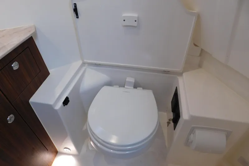 Slide: The Image of 2023 Pursuit OS 325 Offshore boat bathroom with modern toilet and wooden cabinetry. - 51