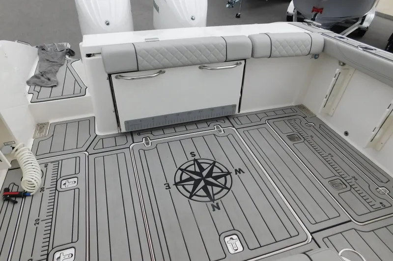 Slide: The Image of 2023 Pursuit OS 325 Offshore boat deck with compass design and storage compartments. - 9