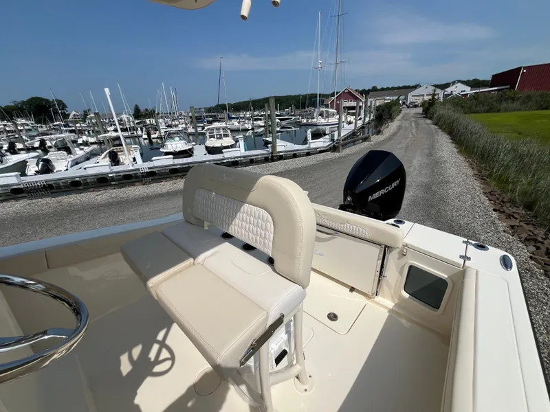 Slide: The Image of 2027 Scout 220XSF at a marina, featuring beige seating and a Mercury engine. - 7