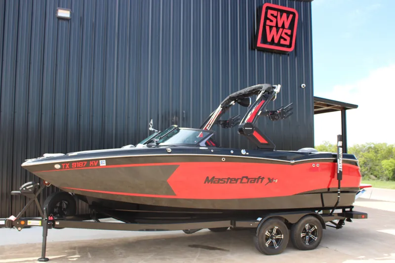 The Image of 2024 MasterCraft XStar S boat in red and black, parked on a trailer. - 0