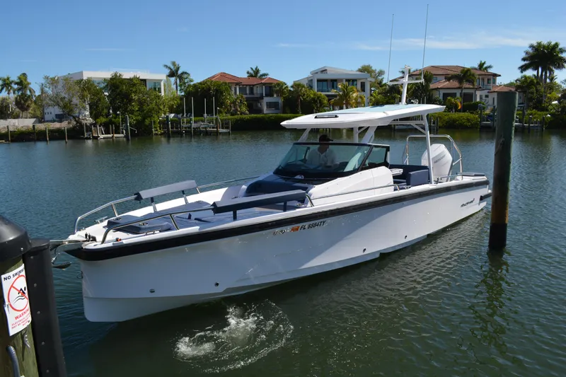 The Image of 2025 Axopar 29 Sun-Top boat cruising on a sunny waterfront with modern homes. - 0