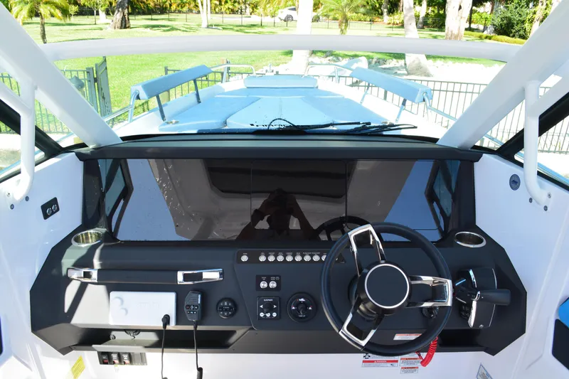 Slide: The Image of 2025 Axopar 29 Sun-Top boat dashboard with steering wheel and control panel. - 11