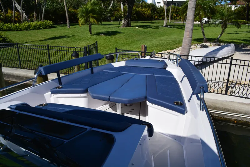 Slide: The Image of 2025 Axopar 29 Sun-Top boat with blue seating, docked near lush greenery. - 15