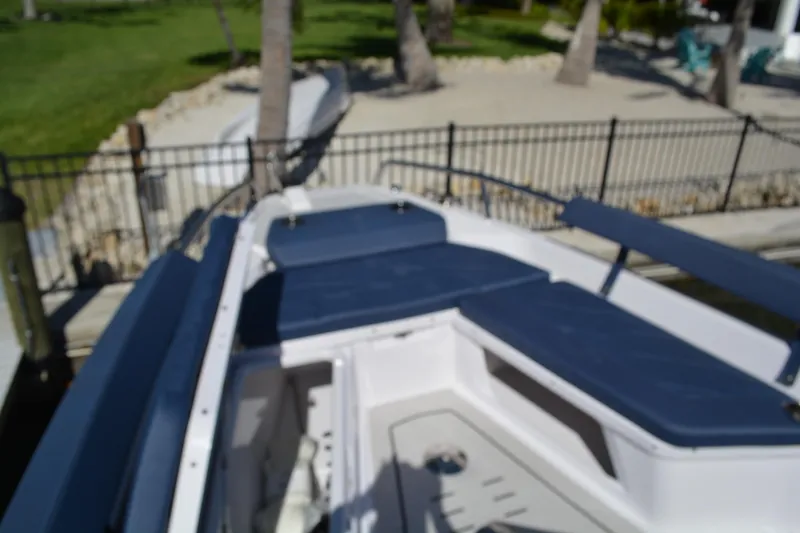 Slide: The Image of 2025 Axopar 29 Sun-Top boat with blue seating, docked near a sandy area. - 16