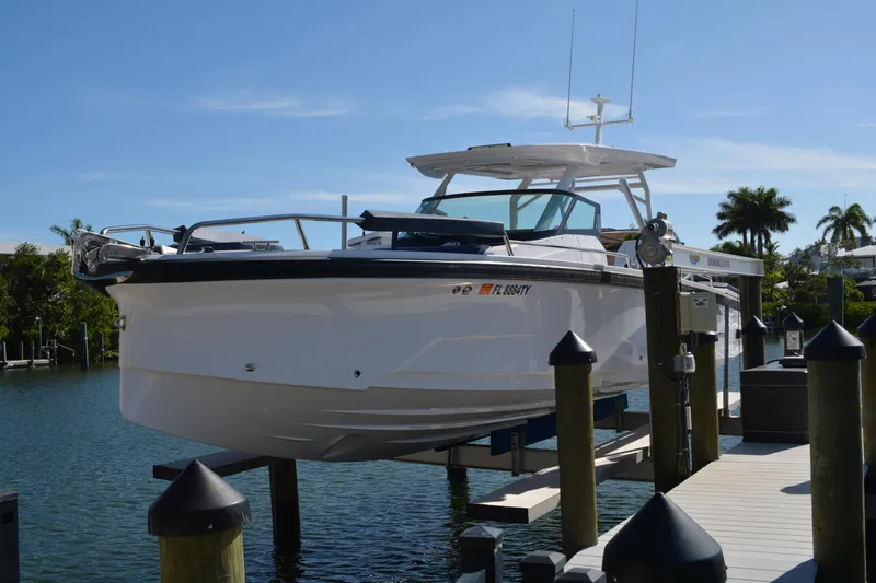 Slide: The Image of 2025 Axopar 29 Sun-Top boat docked on a sunny day, surrounded by water and palm trees. - 2