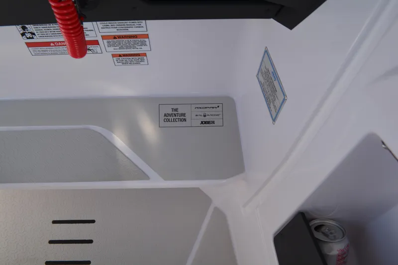 Slide: The Image of Interior detail of 2025 Axopar 29 Sun-Top boat, featuring safety labels and storage area. - 21