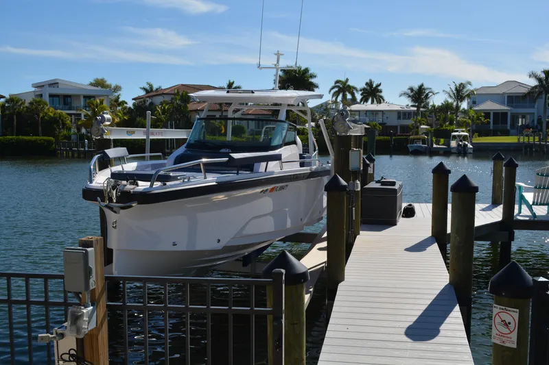 Slide: The Image of 2025 Axopar 29 Sun-Top boat docked at a marina with waterfront homes. - 23