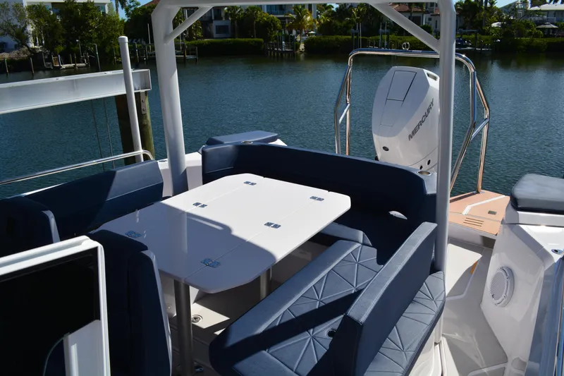 Slide: The Image of 2025 Axopar 29 Sun-Top boat interior with seating and table, docked by the water. - 8