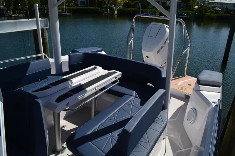 Slide: The Image of 2025 Axopar 29 Sun-Top boat interior with seating and Mercury engine, docked by the water. - 9
