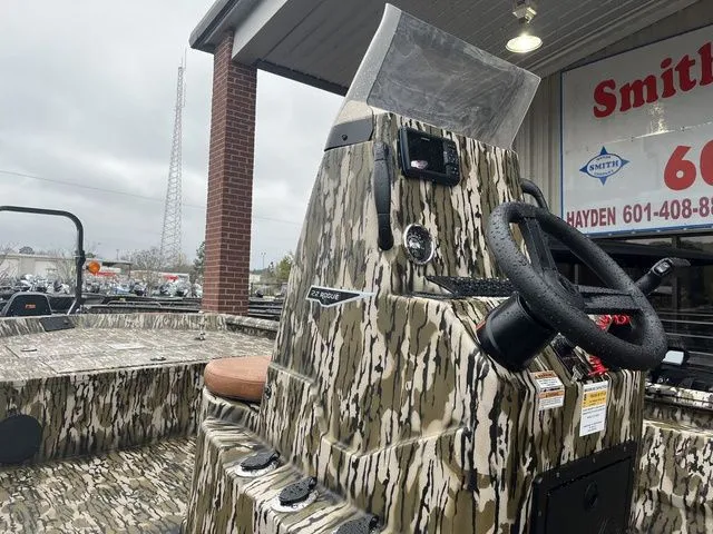 Slide: The Image of 2026 Avid 22 Rogue boat with camouflage design outside a store. - 3