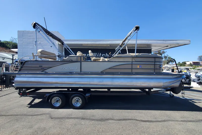 The Image of 2015 Manitou 25 SES Flip pontoon boat on trailer, parked outdoors. - 0