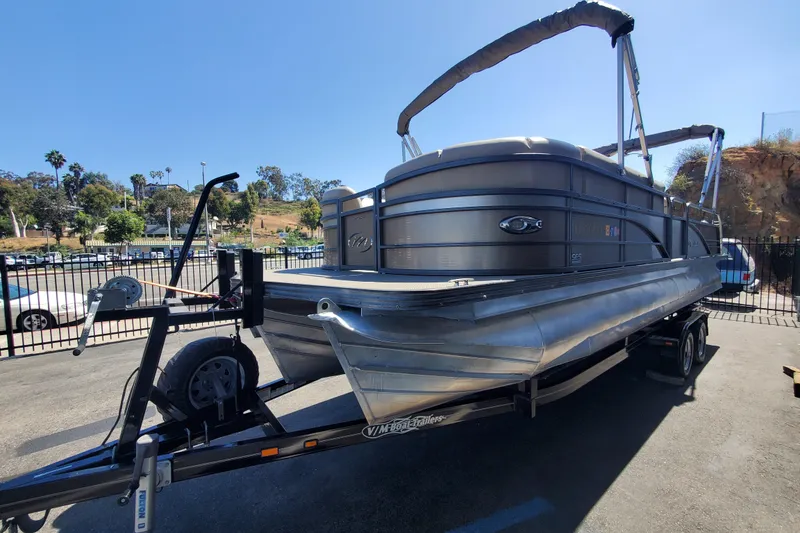 Slide: The Image of 2015 Manitou 25 SES Flip pontoon boat on trailer in sunny outdoor setting. - 1