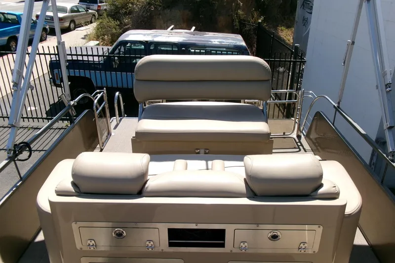 Slide: The Image of 2015 Manitou 25 SES Flip boat interior with beige seating and storage compartments. - 16