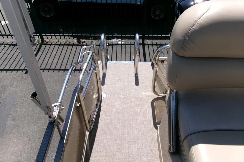Slide: The Image of 2015 Manitou 25 SES Flip boat deck with beige seating and stainless steel railings. - 26