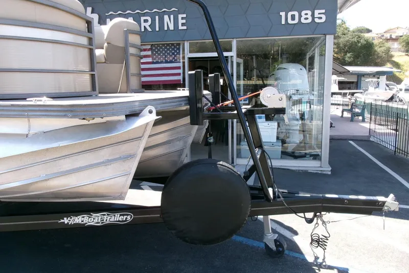 Slide: The Image of 2015 Manitou 25 SES Flip pontoon boat on trailer outside marine shop. - 30