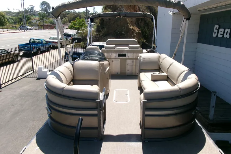 Slide: The Image of 2015 Manitou 25 SES Flip pontoon boat with beige seating and canopy, parked outdoors. - 34
