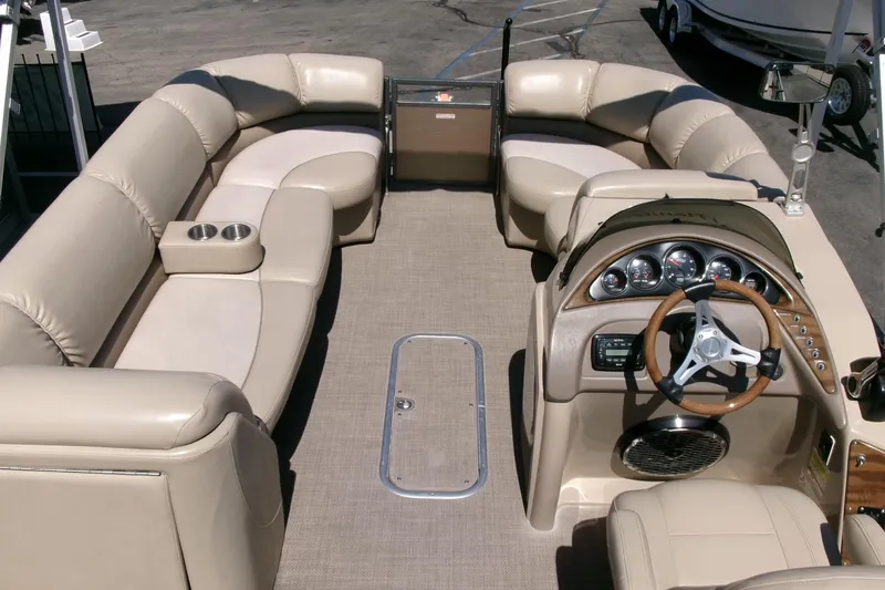 Slide: The Image of 2015 Manitou 25 SES Flip pontoon boat interior with beige seating and modern dashboard. - 5
