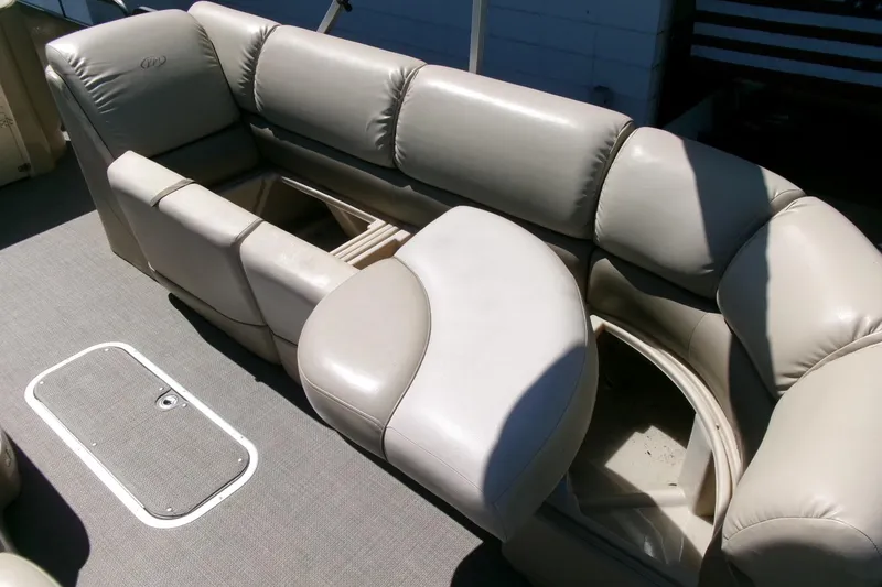 Slide: The Image of 2015 Manitou 25 SES Flip boat interior with beige cushioned seating and storage compartments. - 9