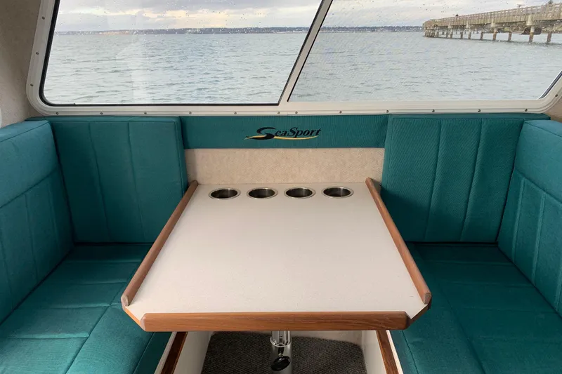 Slide: The Image of Interior of 2026 Sea Sport XL 2400 boat with teal seating and table, overlooking water. - 4