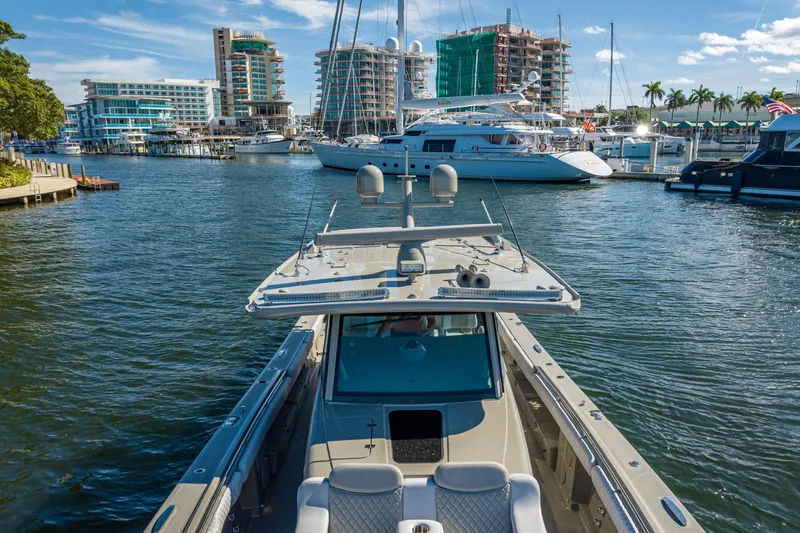 Slide: The Image of 2024 HCB 53 Suenos luxury boat docked in a vibrant marina with modern buildings. - 24