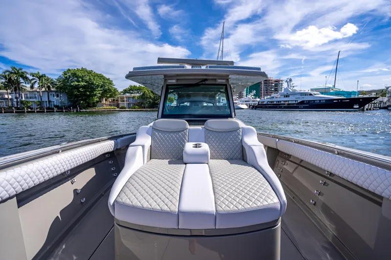 Slide: The Image of 2024 HCB 53 Suenos luxury boat with plush seating, docked in a marina. - 44