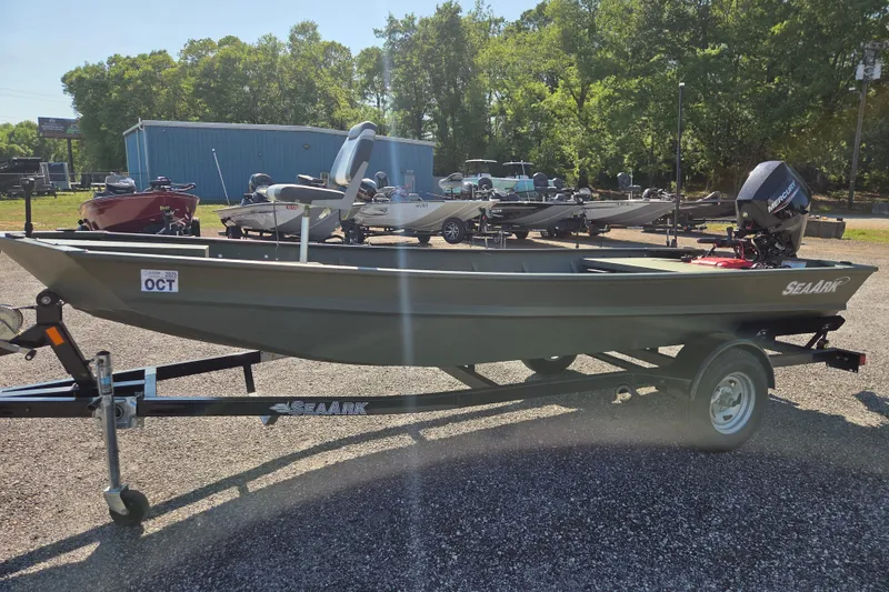 Slide: The Image of 2023 SeaArk 1648 MV boat on trailer, parked outdoors with trees in background. - 4