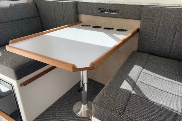 Slide: The Image of 2026 Sea Sport Kenai 2600 interior with gray seating and a wooden-trimmed table. - 13