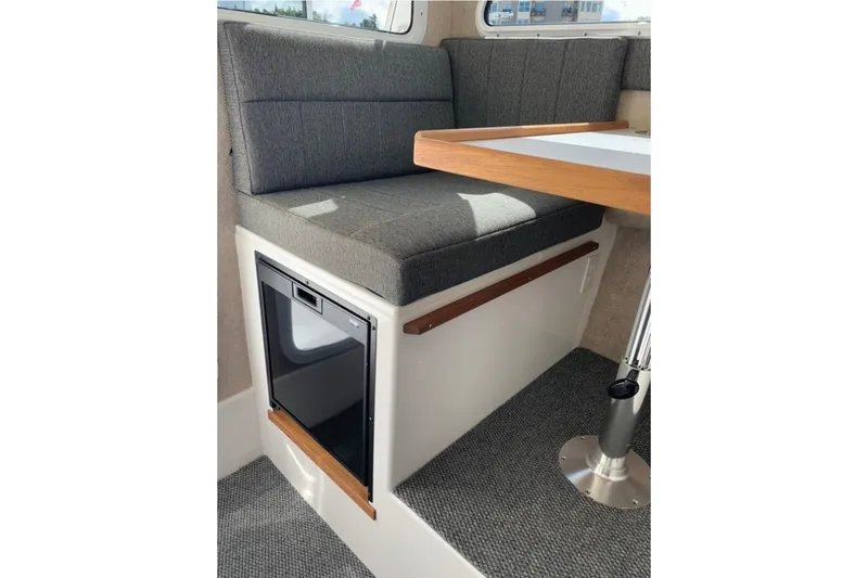 Slide: The Image of Interior of 2026 Sea Sport Kenai 2600, featuring a cushioned seating area and table. - 15