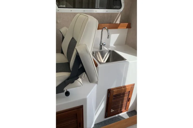 Slide: The Image of Interior of 2026 Sea Sport Kenai 2600 featuring a compact sink and seating area. - 16