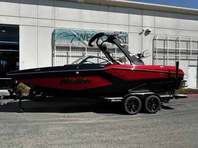The Image of 2026 Malibu Wakesetter 23 MXZ boat in red and black outside a building. - 1