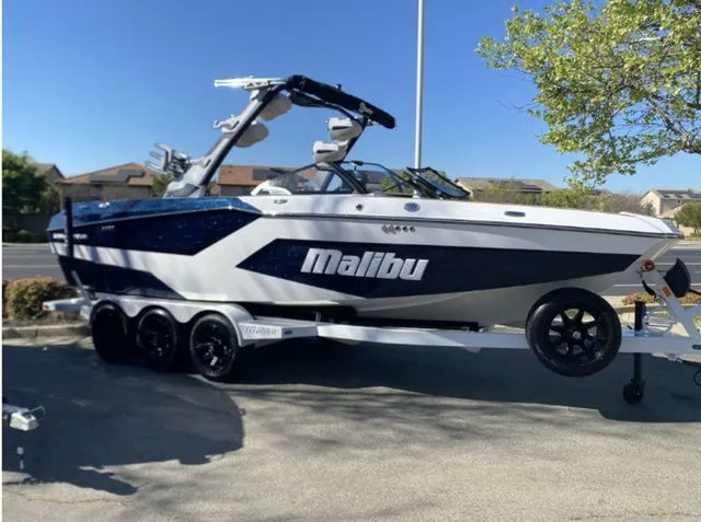 The Image of 2026 Malibu Wakesetter 24 MXZ boat on trailer, sunny day. - 1