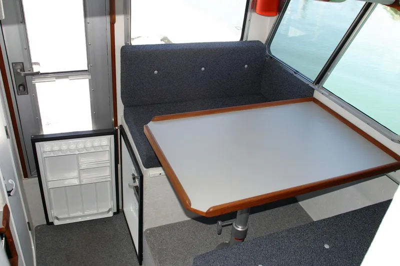 Slide: The Image of Interior of 2026 Sea N Sport Alaskan Pilot 2600 with table and open mini fridge. - 4
