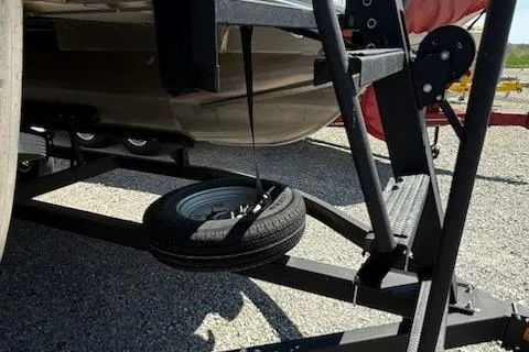 Slide: The Image of 2024 Sun Tracker Bass Buggy 16 XL trailer with spare tire on gravel surface. - 11