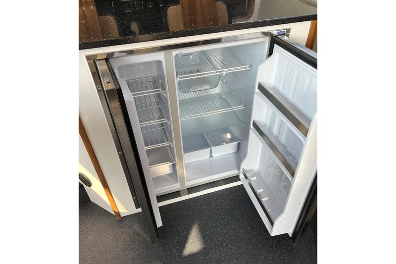 Slide: The Image of Open refrigerator inside 2026 Sea Sport Pacific 3200 boat, showcasing spacious interior and shelving. - 27