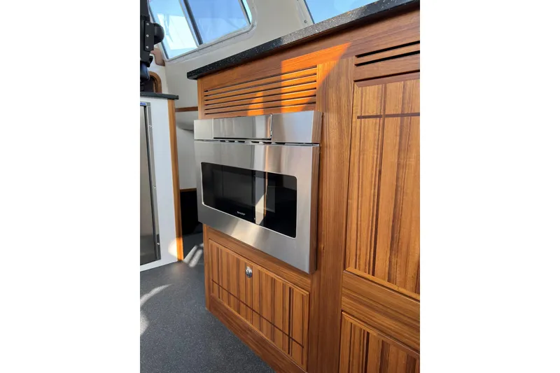 Slide: The Image of Wooden interior of 2026 Sea Sport Pacific 3200 boat with built-in stainless steel microwave. - 28