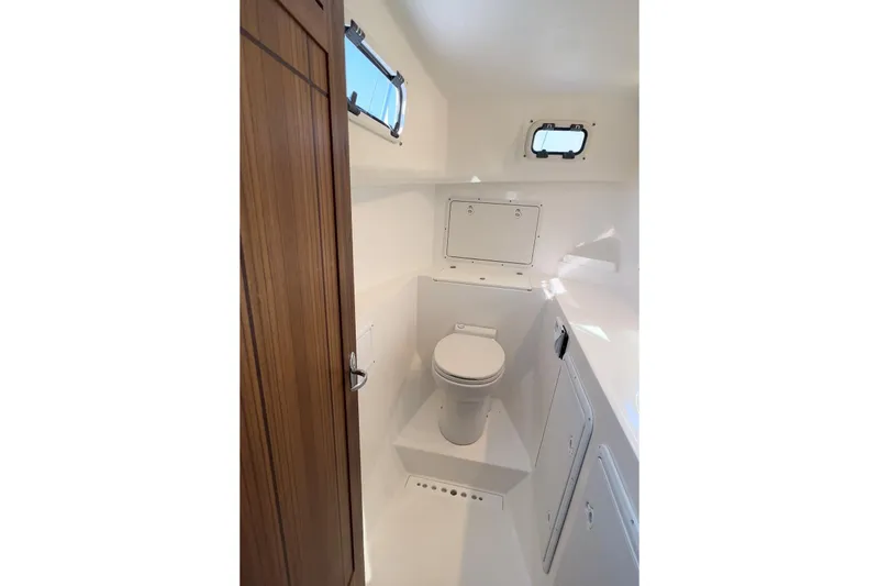 Slide: The Image of Interior of 2026 Sea Sport Pacific 3200 boat bathroom with wooden door and porthole windows. - 7
