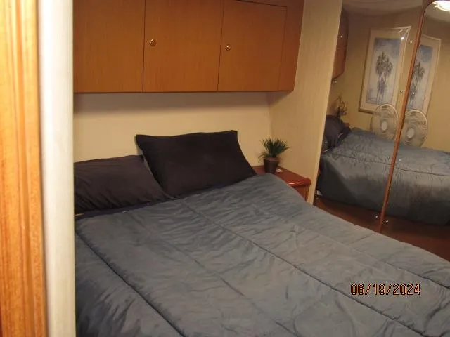 Slide: The Image of Bedroom interior of 2004 Ocean Yachts Super Sport with blue bedding and wooden cabinets. - 22