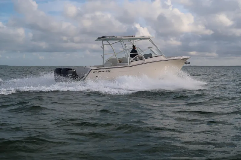 Slide: The Image of 2018 Grady-White Freedom 307 boat cruising on open water under cloudy skies. - 24