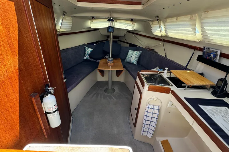 Slide: The Image of Interior of a 2003 Catalina 250 sailboat with cozy seating and compact kitchen area. - 3