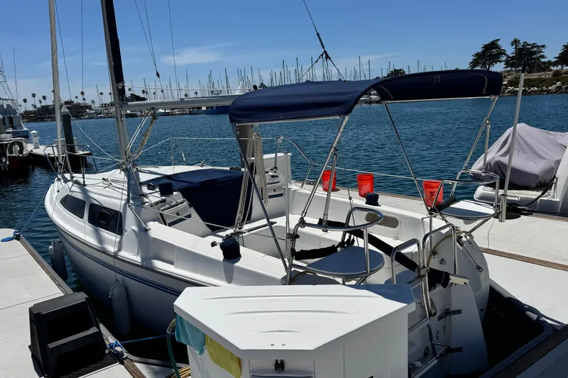 Slide: The Image of 2003 Catalina 250 sailboat docked at marina, featuring blue canopy and calm waters. - 6