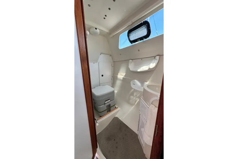 Slide: The Image of Interior of a 2003 Catalina 250 sailboat bathroom with compact toilet and window. - 7
