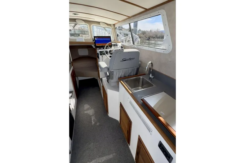 Slide: The Image of Interior of 2026 SeaSport Explorer 2400 boat with helm, sink, and seating area. - 5