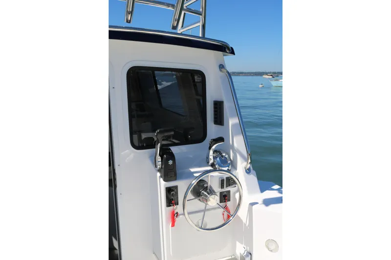 Slide: The Image of 2026 SeaSport Explorer 2400 boat helm with steering wheel and controls, docked on calm water. - 9