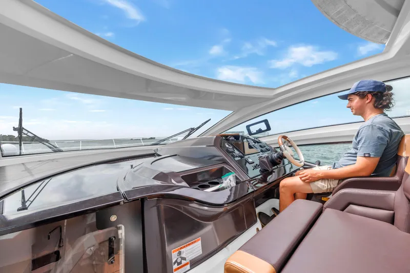 Slide: The Image of Person steering a 2019 Beneteau Gran Turismo 46 yacht under a clear blue sky. - 34