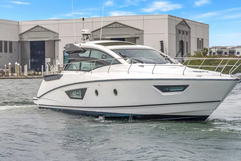Slide: The Image of 2019 Beneteau Gran Turismo 46 yacht cruising near a marina, showcasing sleek design. - 68