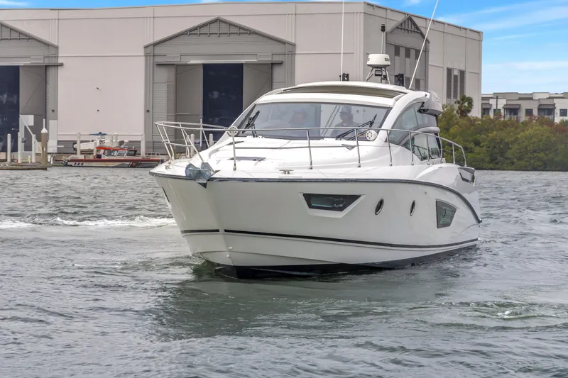 Slide: The Image of 2019 Beneteau Gran Turismo 46 yacht cruising near a marina, showcasing sleek design and elegance. - 75